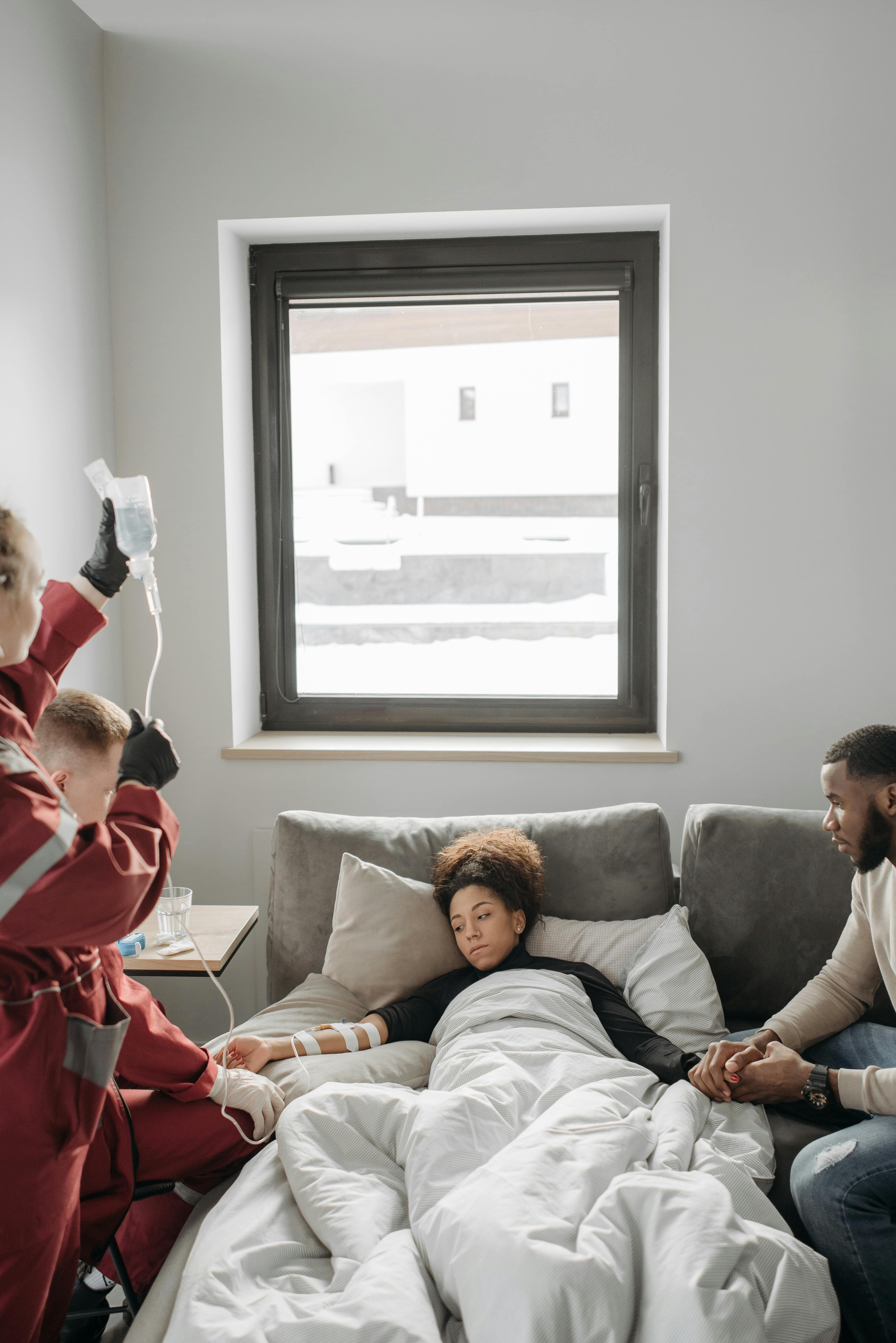 Emergency responders attend to a patient in a cozy room, administering care while family members offer support nearby.